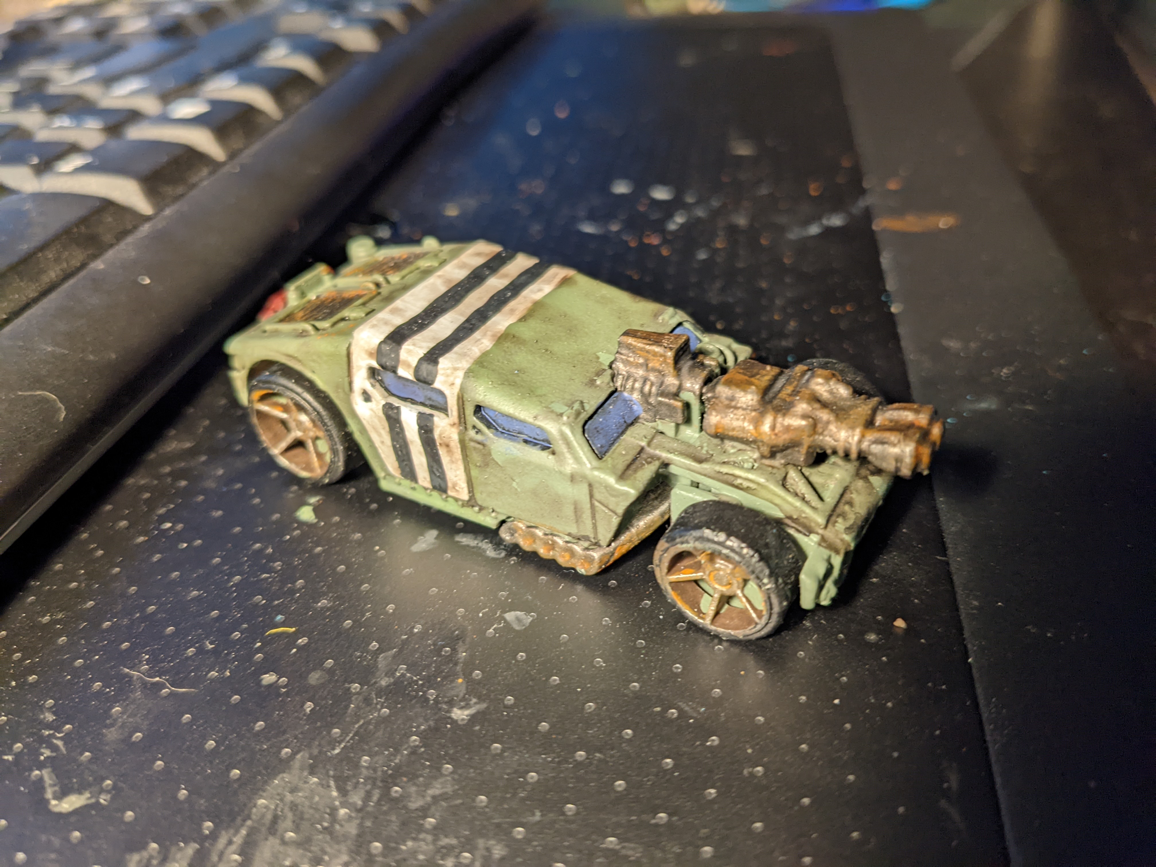 A drab green hotrod with a flamethrower on the hood.